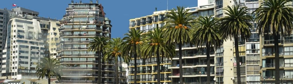 Row of waterfront buildings by palm trees in Vina del Mar, along the central coast of Chile.